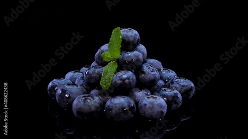 Wallpaper Mural Blueberries rotating on a black background close up. Fresh bio blueberries with leaves of mint, sprinkle with drops of water, rotating on black plate. Raw, organic healthy forest berries Torontodigital.ca