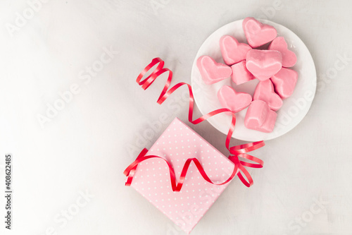 Happy Valentines Day. Gift box with pink chocolate hearts, greeting card and ribbon. With space for text