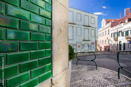 A street view of a wall of a traditional Portuguese house in Lisbon decorated by vivid green azulejo tiles. 