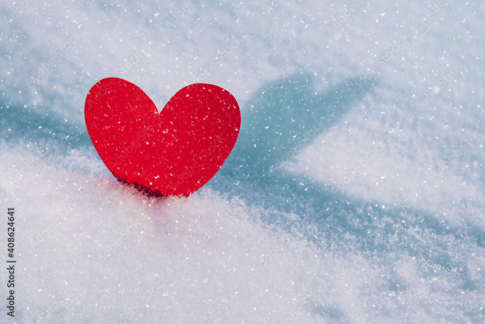 Lonely valentine. Red heart in cold, frosty morning snow. Valentine's Day greeting card. A symbol of love and romantic relationships. Congratulations on holiday of February 14. Copy space for text