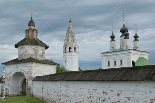Ancient orthodox monastery Aleksandrovskiy in 1000-years-old town of Suzdal, Russian Golden Ring. Black crow sits on the monastery wall.