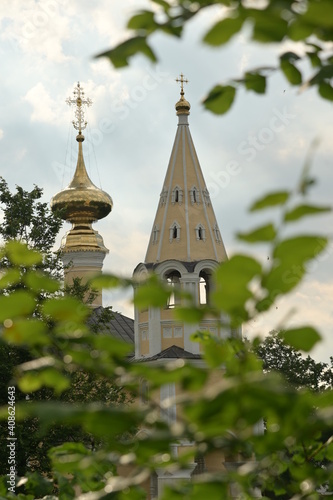 Orthodox church domes with christian cross seen through fresh green leaves in summer. Old town of Suzdal, Russian 