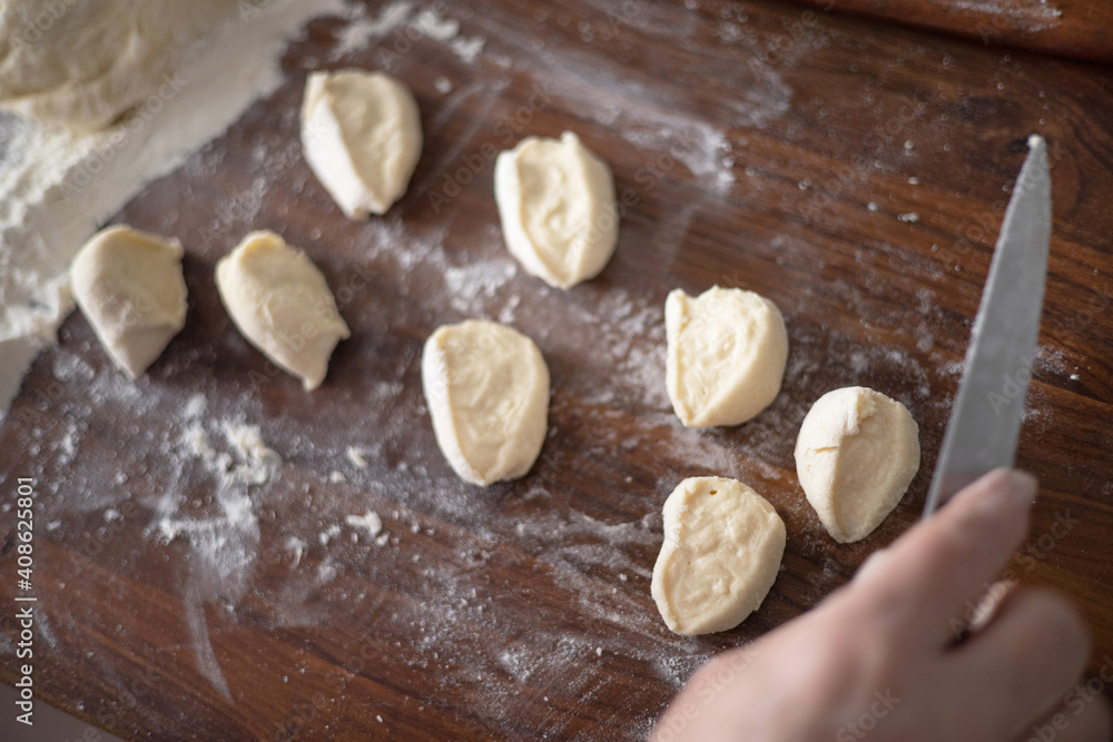 Fototapeta premium Senior woman hands rolling out dough in flour with rolling pin in her home kitchen