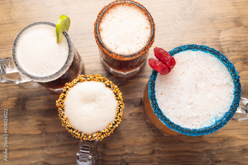 Michelada beer on wooden table. Four beers. Mexican drink. Concept of chelada beer. Four michelada beers.
