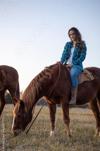 Girl Smiling at Camera on Horse Grazing in Field
