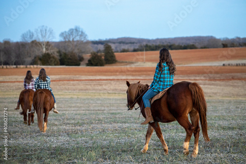 Girls Riding Horses through Pasture