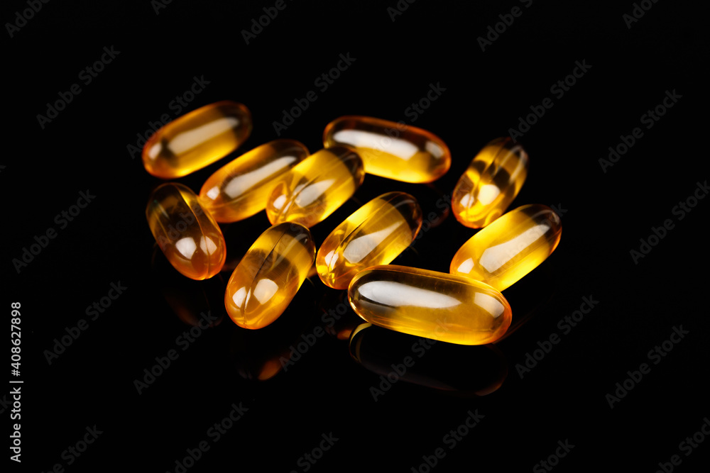 Capsules with fish oil on a black background. The use of vitamin D, omega-3. Health concept