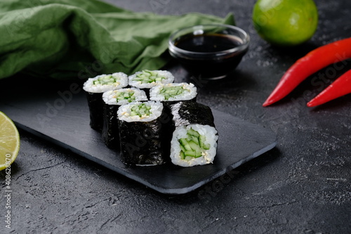 Vegetarian sushi roll with cucumber on black background