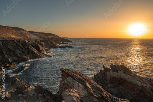 Sunset on the rocky coast with calm sea
