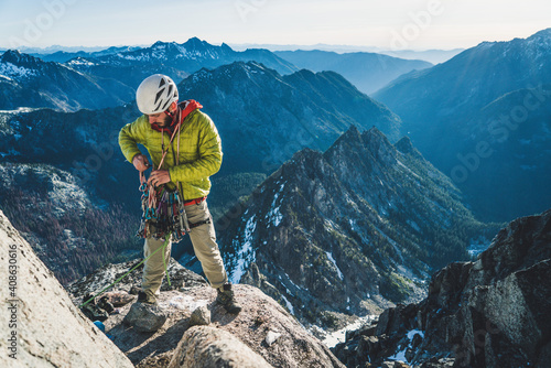 Man sorting climbing gear on alpine rock climb in Washington