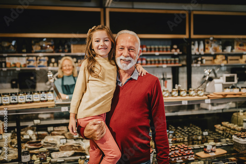 Happy grandfather shopping together with his granddaughter in grocery store or supermarket.