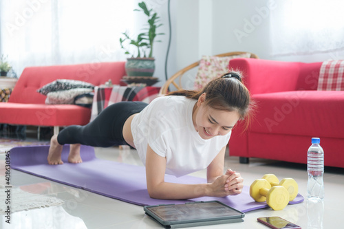 Fit woman doing yoga plank and watching online tutorials. photo