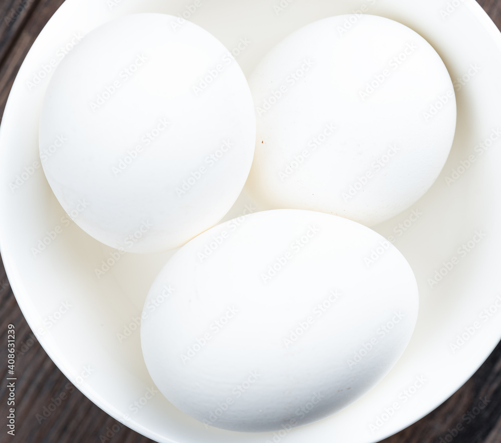 Close-up of chicken eggs with a white shell in a white cup.