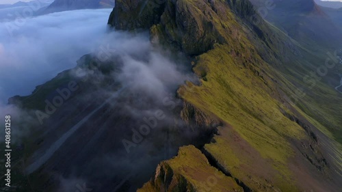 Drone aerial footage of Coastal mountains and cliffs near Stokkness at sunrise with clouds in Iceland photo