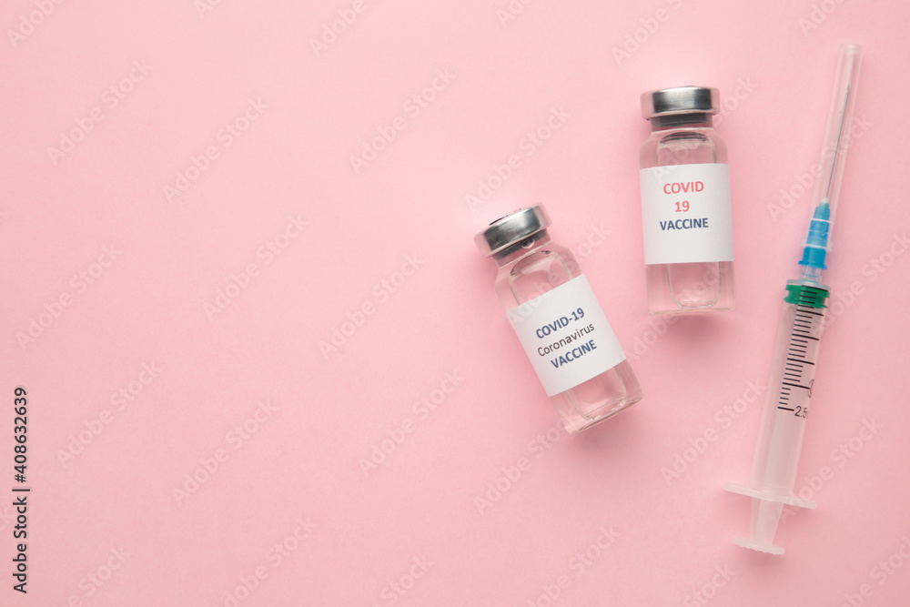 Coronavirus COVID-19 vaccine vials and syringe on pink background with copy space. Coronavirus COVID-19 vaccine vials and syringe on pink background with copy space.