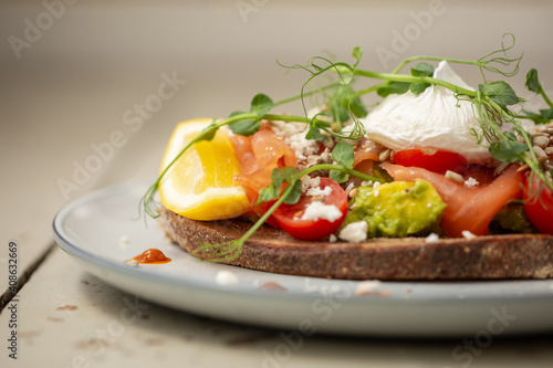 Smoked salmon and avocado on toast, topped with poached egg and dressing