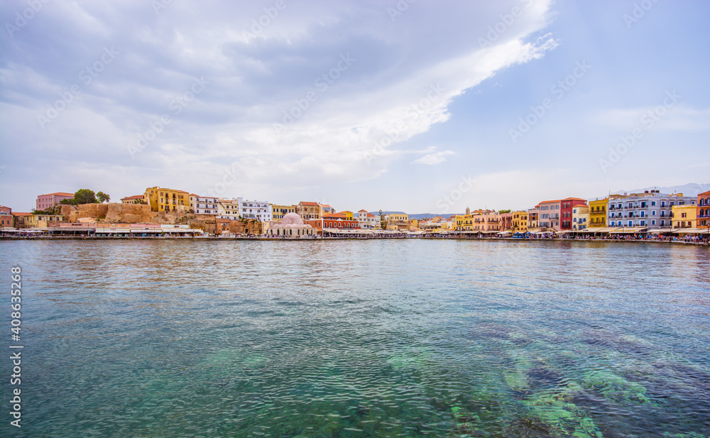 azure turquoise blue transparent sea and the city of Chania on the horizon against the blue sky with white clouds on a summer day on the island of Crete in Greece