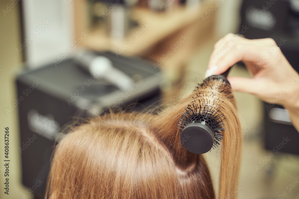 Fototapeta premium Long hair woman. Hairdresser treatment. Repair procedure. Haircut at salon. Bride hairstyle. Master hand with brush. Adult female person. Closeup view. Lady preparation. Blonde dry