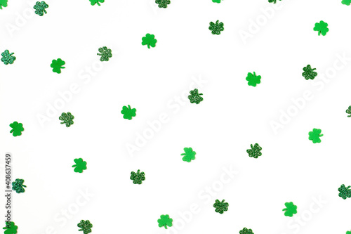 Green shiny and shimmering shamrock confetti sparse on white background Happy St. Patrick's Day Spring 17 march backdrop with lucky clovers. 