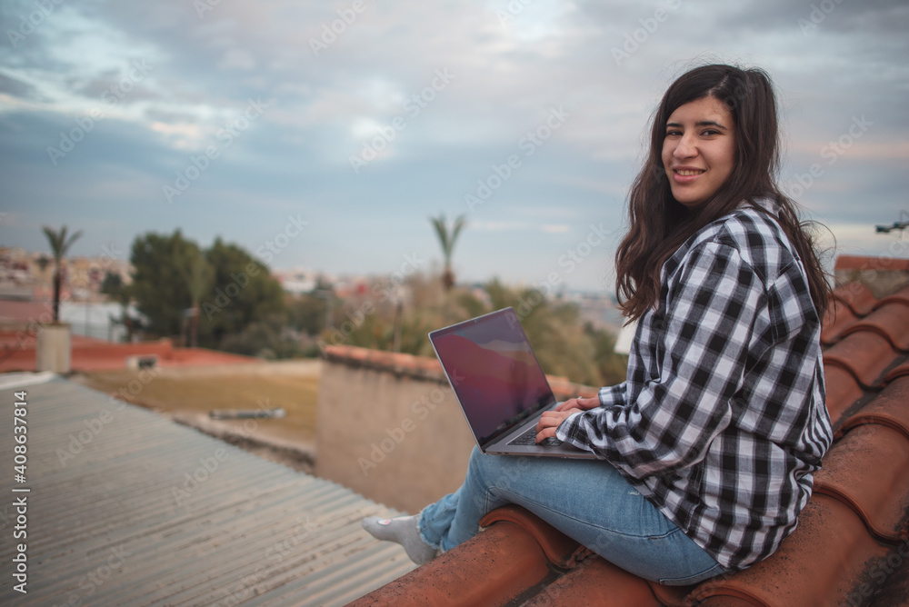 Fototapeta premium Creative girl works from the roof of her house