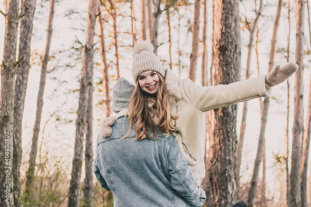 The guy carries the girl on his shoulder and she smiles against the background of a pine forest
The guy carries the girl on his shoulder and she smiles against the background of a pine forest