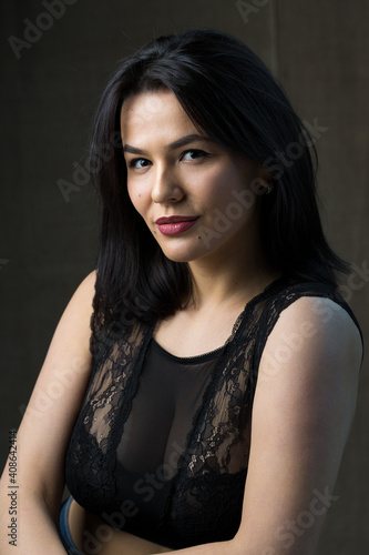 Portrait of a young sexy brunette girl in a lace top in dramatic tones. Vintage photo.