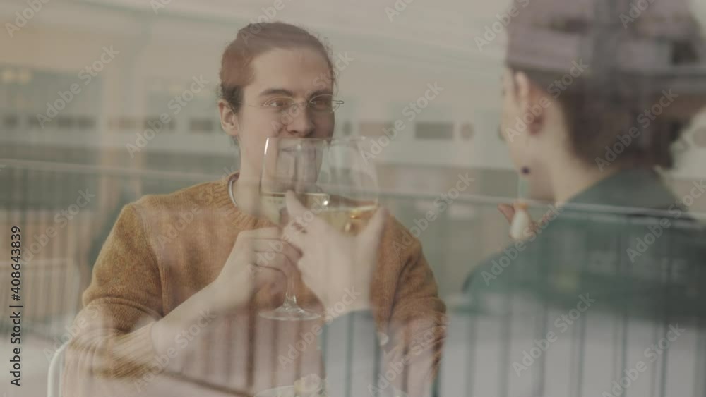 Rear view of cheerful young Caucasian man having dinner with girlfriend in restaurant. Young people drinking wine during meal Rear view of cheerful young Caucasian man having dinner with girlfriend in restaurant. Young people drinking wine during meal