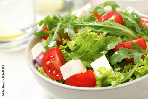Delicious salad with arugula and vegetables on white table, closeup