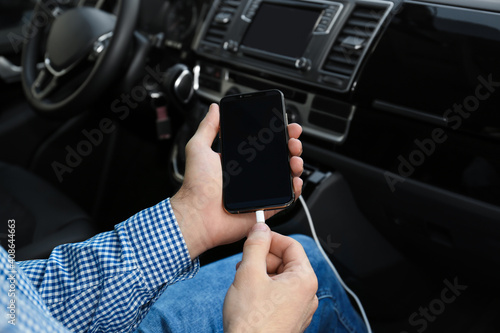 Man charging phone with USB cable in car