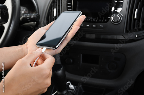 Person charging phone with USB cable in car