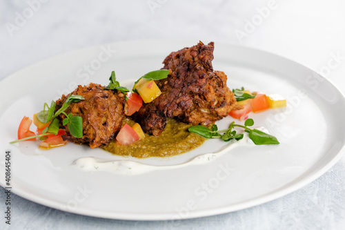 Onion bhaji with chili sauce on a white plate