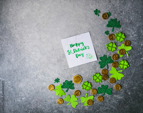 Decorative clover leaves, green gifts box, coins on stone background, flat lay. St. Patrick's Day celebration. Card Happy St. Patrick's Day