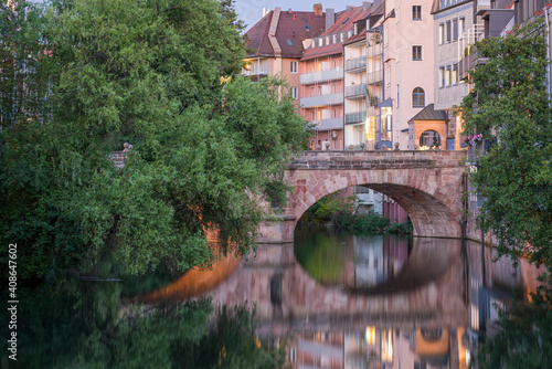 Residential buildings and arch of Karlsbrucke bridge on Pegnitz river at dusk, Nuremberg, Germany photo