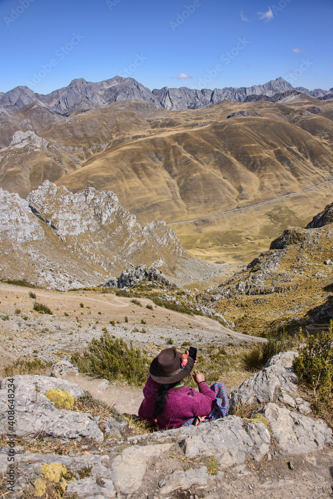 Fototapeta premium A Cholita enjoying the views from the Cancanapunta pass on the Cordillera Huayhuash circuit, Ancash, Peru
