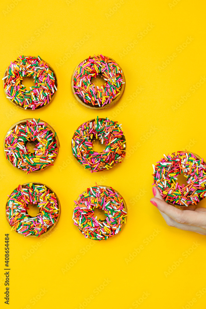 hand holding sprinkle donuts on yellow