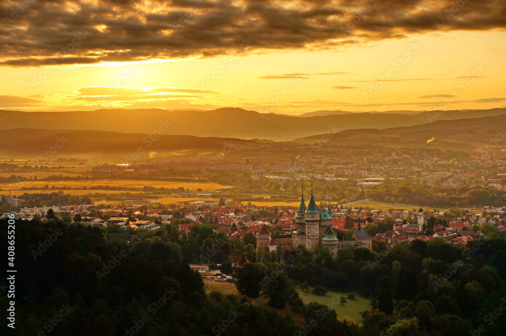Beautiful aerial view on Bojnice castle and town of Bojnice in Slovakia in a warm yellow light at sunrise, with interesting black clouds in the sky