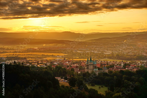 Beautiful aerial view on Bojnice castle and town of Bojnice in Slovakia in a warm yellow light at sunrise, with interesting black clouds in the sky © Nina