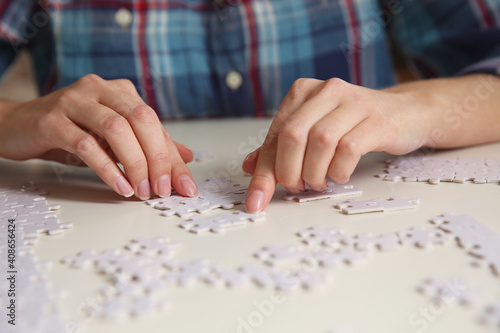 Young woman playing with puzzles at table, closeup