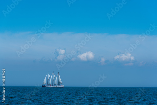Full-rigged sailing ship in the endless blue, the sea and the sky with beautiful clouds, a romantic voyage 