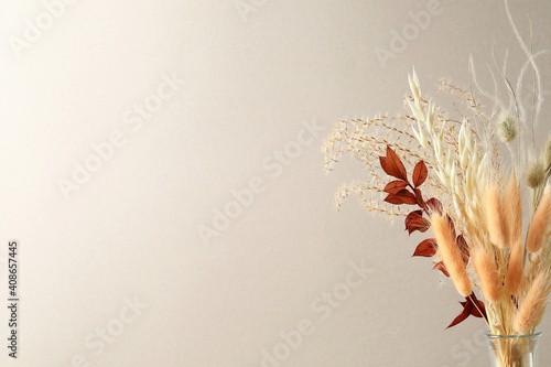 Dried flowers in vase against light background. Space for text photo