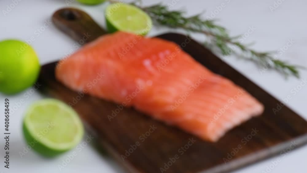 Salmon fish fillet on wooden cutting board with lime and rosemary. Shift focus. Concept of healthy seafood. 4K video Salmon fish fillet on wooden cutting board with lime and rosemary. Shift focus. Concept of healthy seafood. 4K video