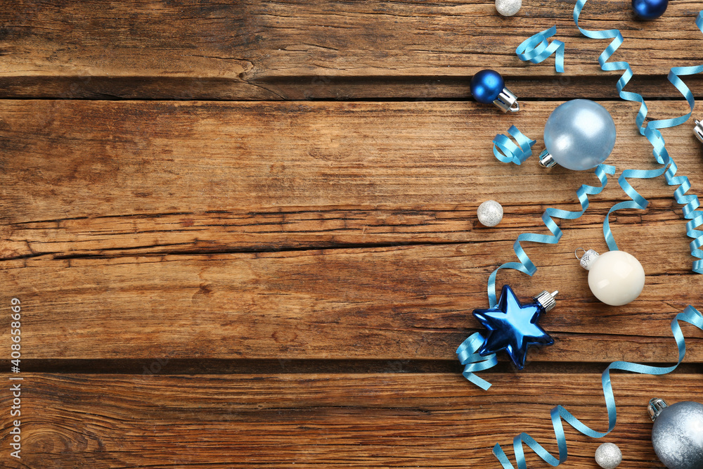 Blue serpentine streamers and Christmas baubles on wooden background, flat lay. Space for text