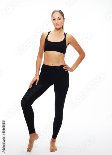 Portrait of beautiful young woman wearing sportswear working out in studio. Fit sporty girl doing yoga. Full length.