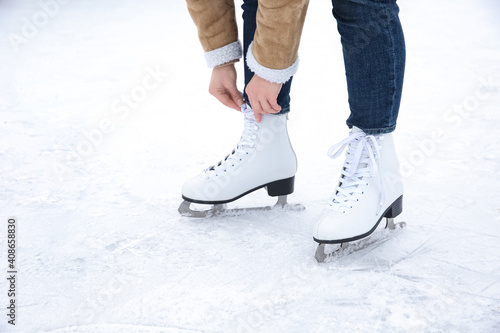Woman lacing figure skate on ice rink, closeup
