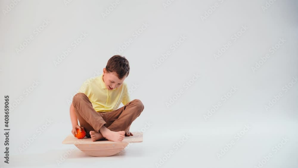 a little boy balancing on the simulator throws up the ball and tries to catch it, keeping his balance. the child performs exercises, training of the vestibular apparatus a little boy balancing on the simulator throws up the ball and tries to catch it, keeping his balance. the child performs exercises, training of the vestibular apparatus