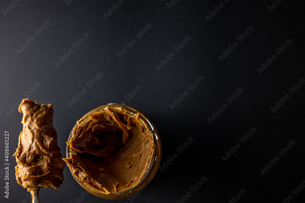 An open jar of peanut butter with a spoon An open jar of peanut butter with a spoon
