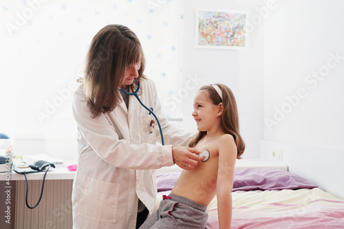 lateral view of a pediatric doctor examine little happy girl wit photo