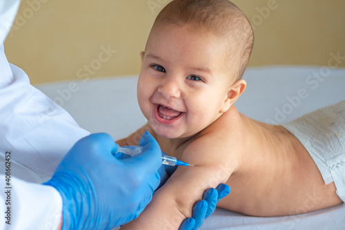 A doctor giving a vaccine to a baby in the hand close-up. The child is happy and smiling