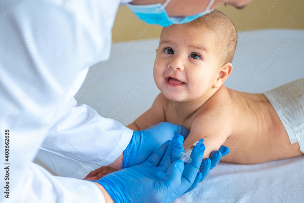 A doctor giving a vaccine to a baby in the hand. Happy child looks at the doctor A doctor giving a vaccine to a baby in the hand. Happy child looks at the doctor