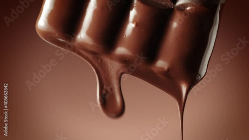 Melted chocolate dripping from a chocolate bar over a dark brown background, vertical camera movement. Chocolate dessert. Confectionery concept backdrop.